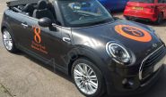 MINI Convertible fully wrapped in a pearlescent black vinyl car wrap with gloss orange cut vinyl graphics